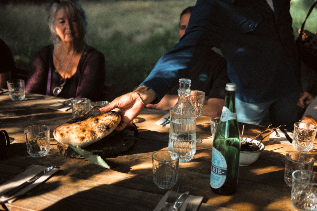 A flatbread straight from the oven set down on the long table.
